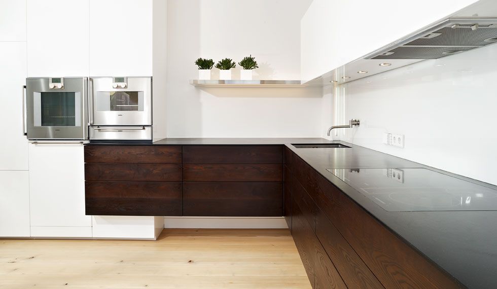 Eine Küche mit Holzschränken und schwarzen Arbeitsplatten