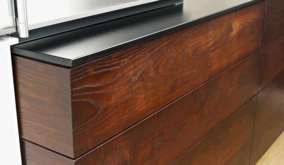 Eine Nahaufnahme einer Holzkommode mit einer schwarzen Arbeitsplatte.