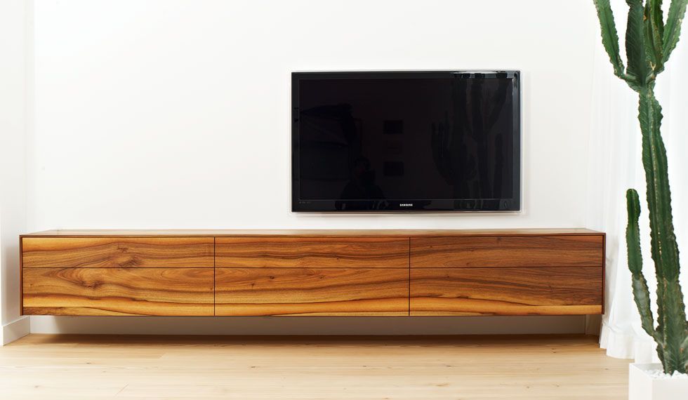 Ein Flachbildfernseher ist an der Wand über einem Entertainment-Center aus Holz angebracht.