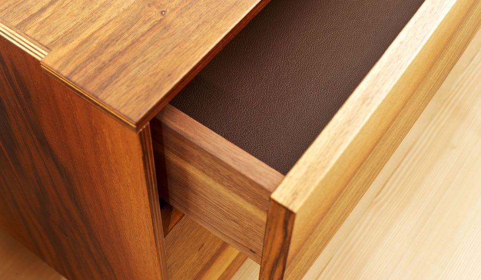 Eine Holzschublade mit einem braunen Teppich darin.