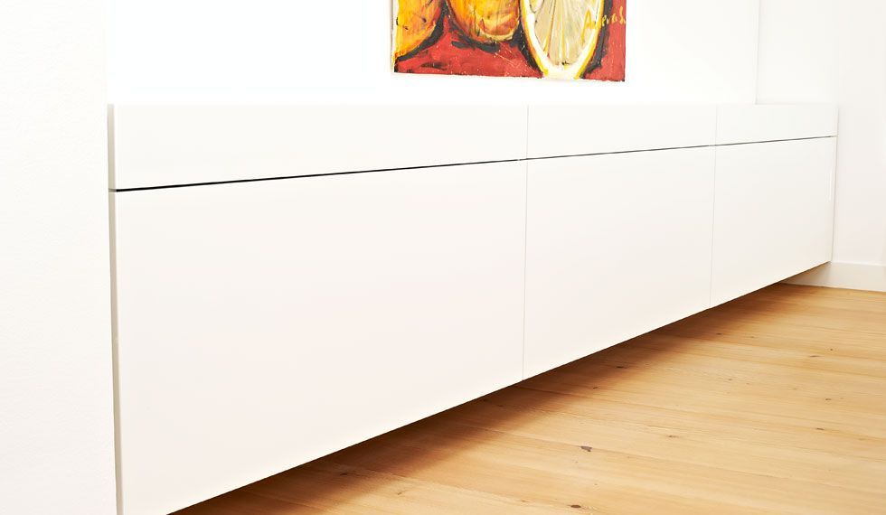 Ein weißer Schrank mit einem Bild von Orangen an der Wand darüber.