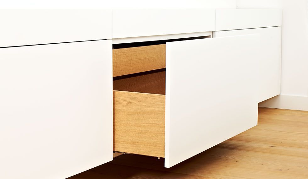 Ein weißer Schrank mit einer Holzschublade darin.