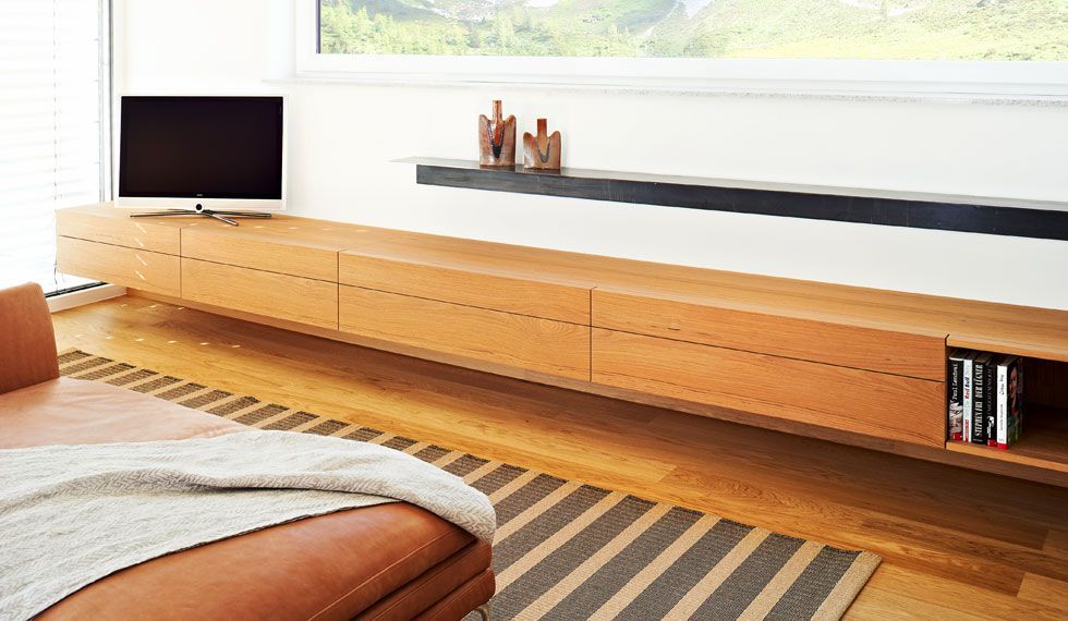 Ein Wohnzimmer mit Sofa, Fernseher und gestreiftem Teppich.