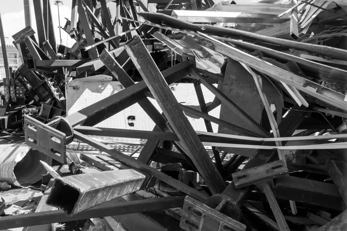 Restos de vigas y estructuras metálicas retorcidas, probablemente de un edificio derrumbado, en blanco y negro.