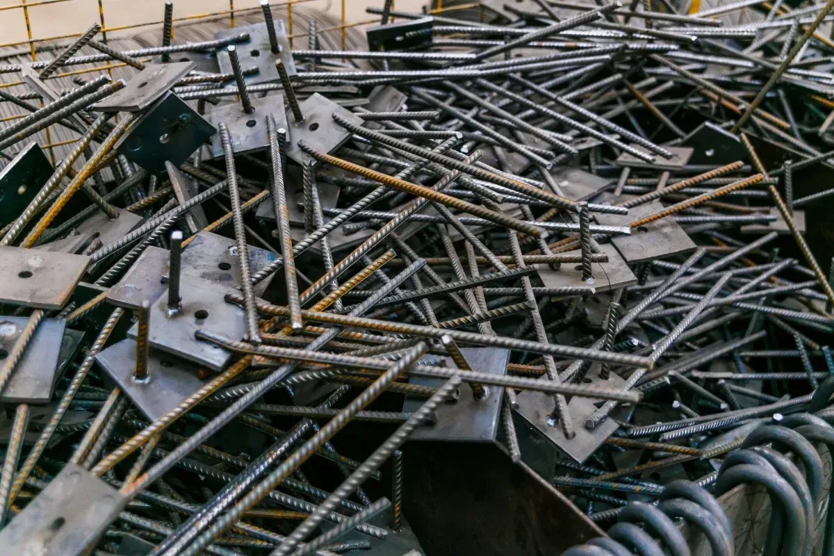 Pila de placas de anclaje de acero con varillas en una fábrica o en una obra.