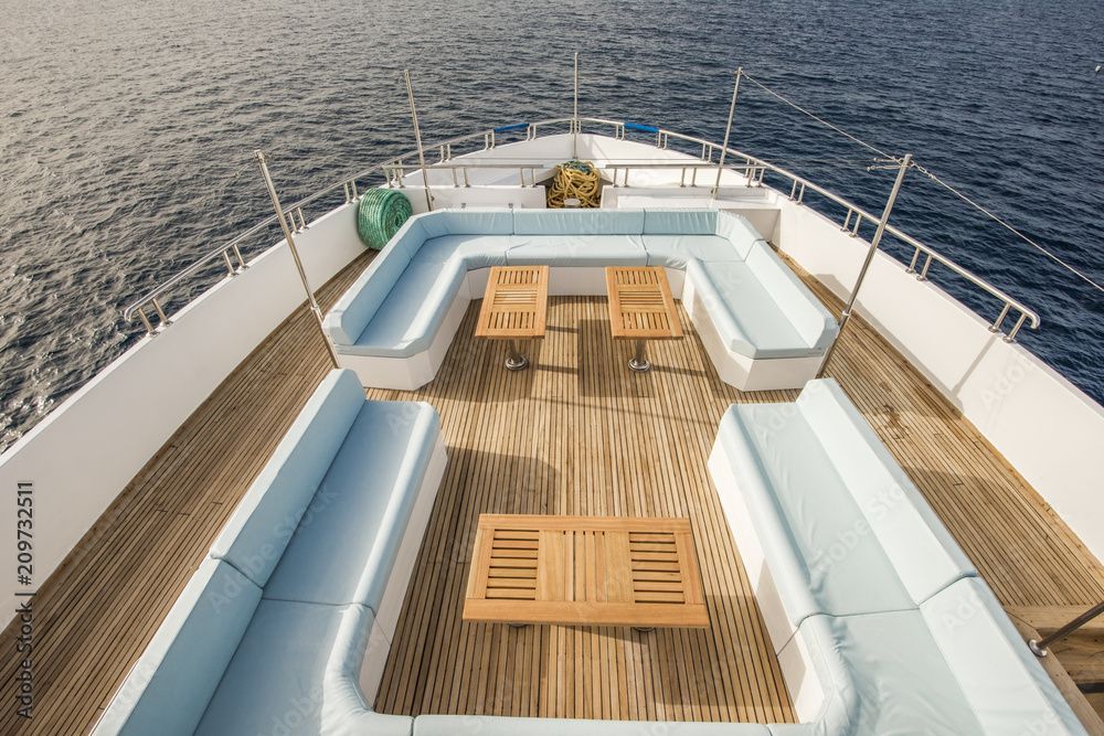 Bugdeck der Yacht mit weissen Sitzgelegenheiten, Holzboden und Blick auf das offene Meer
