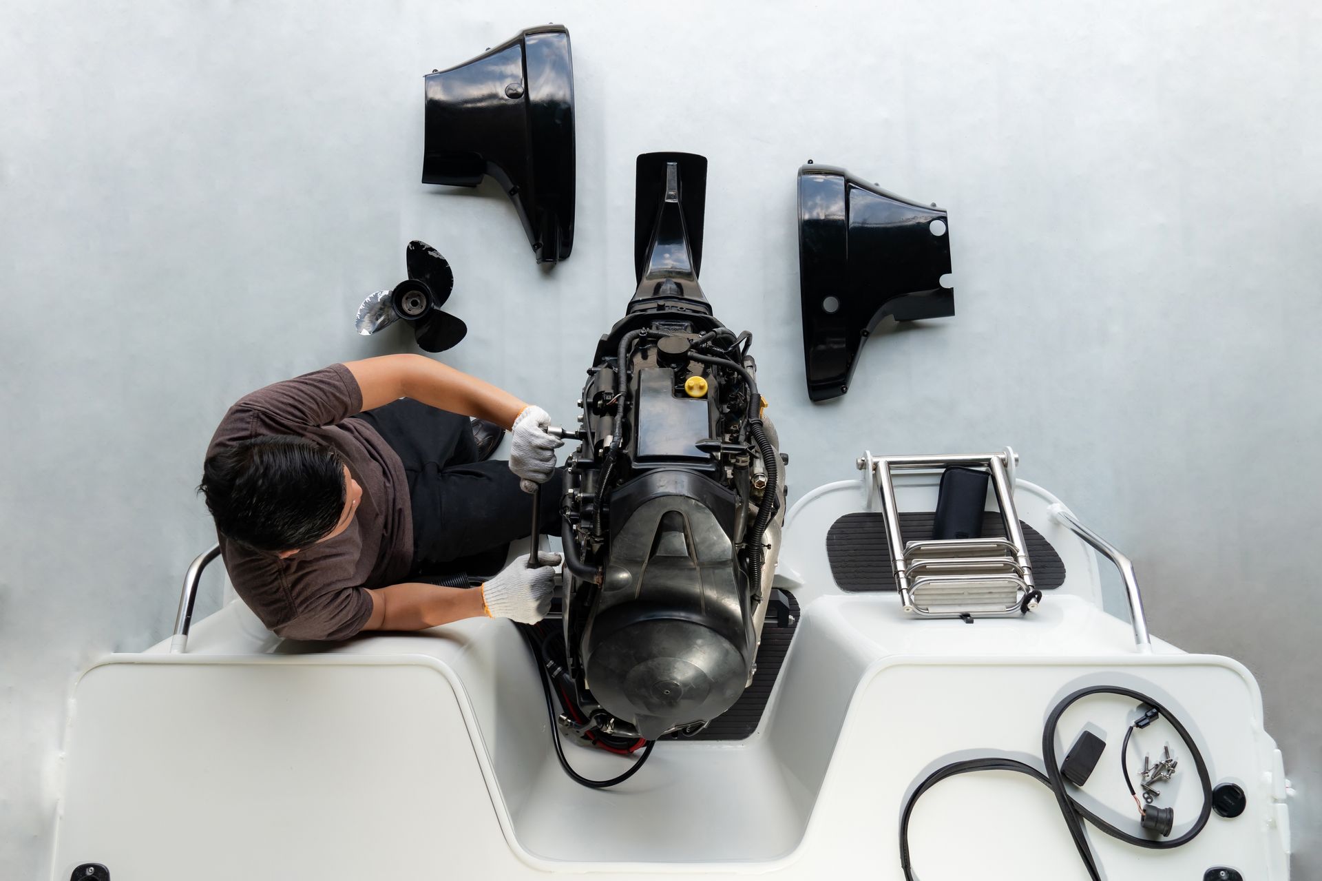 Ein Techniker untersucht ein schwarzes mechanisches Gerät auf einem Tisch, in dessen Nähe lose Teile und Werkzeuge liegen.