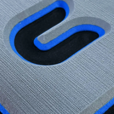 Nahaufnahme einer strukturierten grauen Oberfläche mit einem blau umrandeten schwarzen Logo-Symbol.