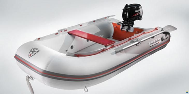 Weisses Schlauchboot mit rotem Zierstreifen und Aussenbordmotor am Heck