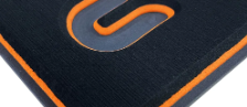 Nahaufnahme eines schwarzen Mauspads mit orangefarbenem Rand und einem stilisierten orange-grauen Logo