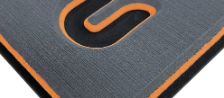 Nahaufnahme eines grauen und orangen Mauspads mit einem stilisierten schwarzen Logo in der Ecke