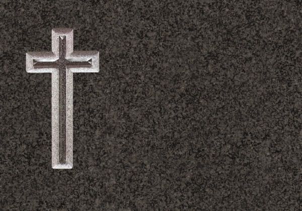 Una cruz está tallada en una lápida sobre un fondo negro.
