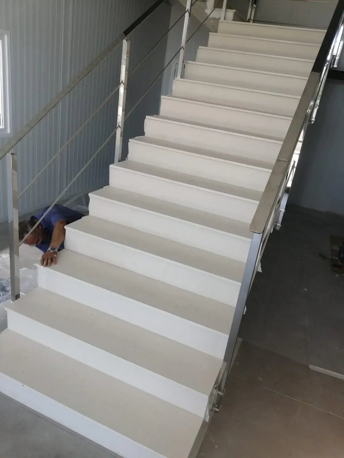 Un hombre está acostado en los escalones de una escalera blanca.