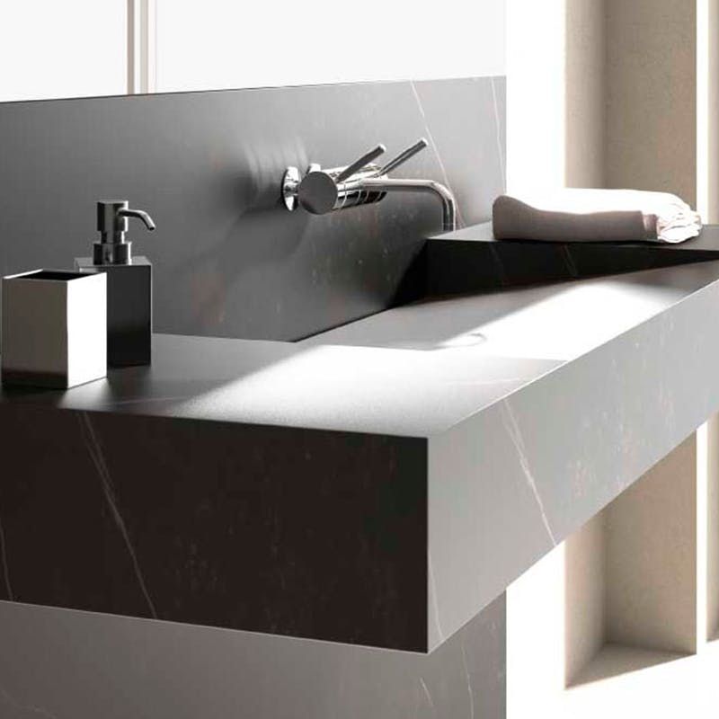 Un lavabo de baño con un dispensador de jabón y una toalla encima.