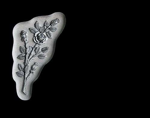 Una estatua de una rosa con hojas sobre un fondo negro.