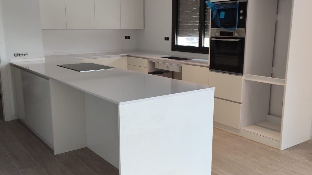 Una cocina con gabinetes blancos y una gran isla en el medio.