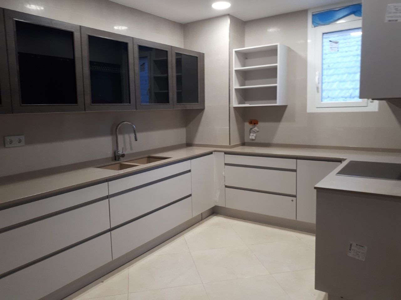 Una cocina con gabinetes blancos, un fregadero y una ventana.