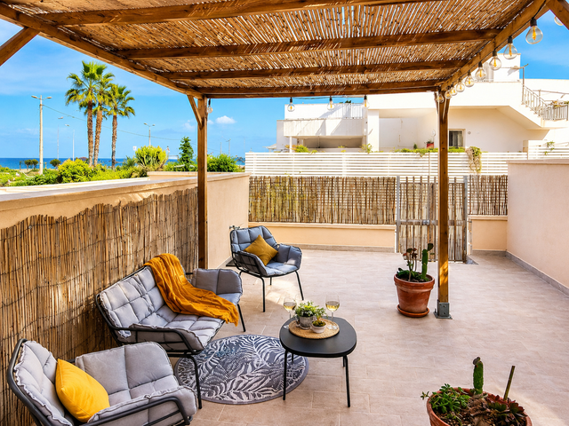 Spacious terrace near the sea with covered pergola and outdoor seating area at Noto da Mare