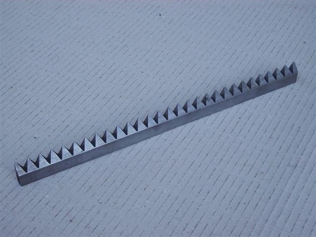 ein Metallstück mit vielen Zähnen auf einer weißen Oberfläche .