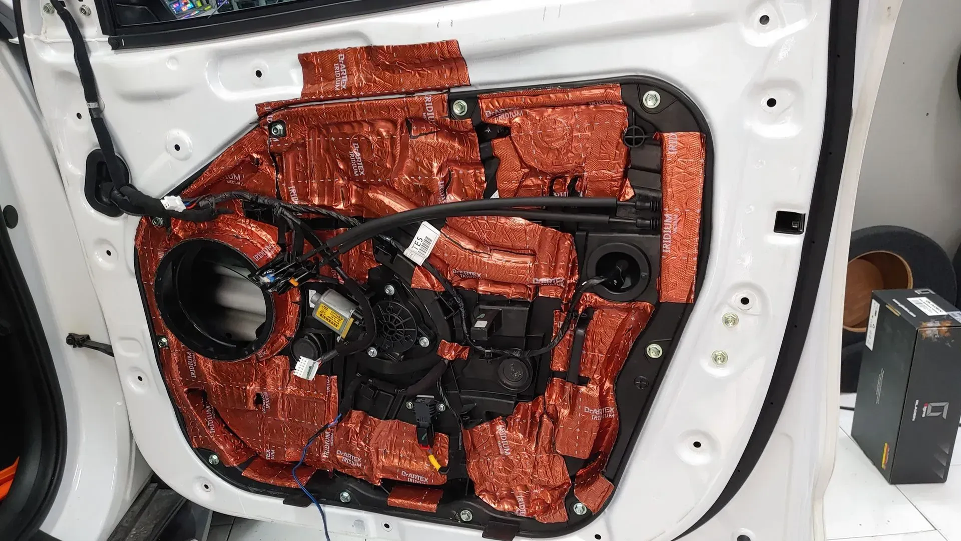 Interior de la puerta del automóvil desmontado con material insonorizante rojo instalado.