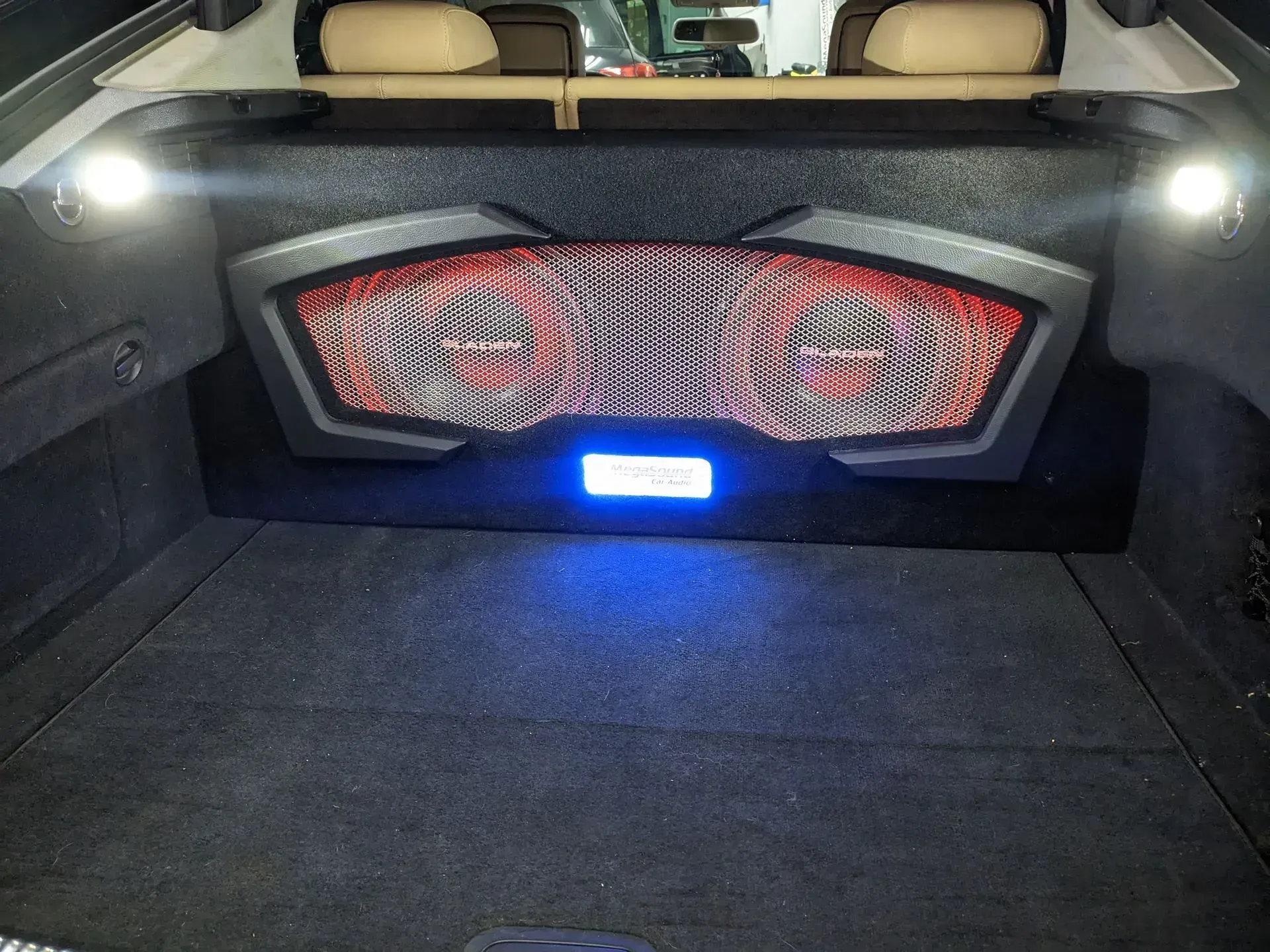 Maletero con sistema de audio personalizado e iluminación azul. Caja de altavoces negra, roja y plateada.