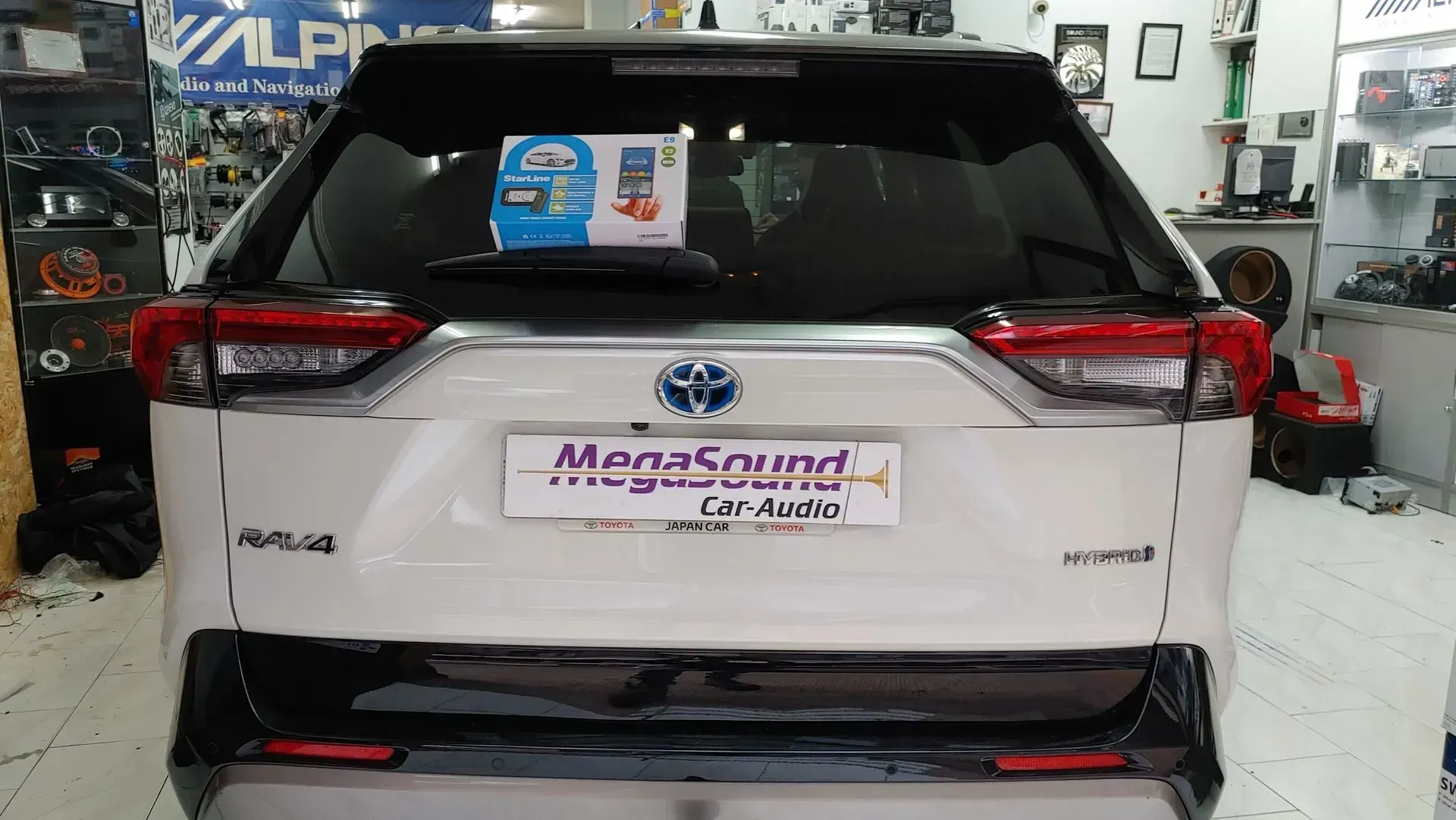 Vista trasera de un Toyota RAV4 Hybrid blanco con parachoques negro estacionado en el interior,