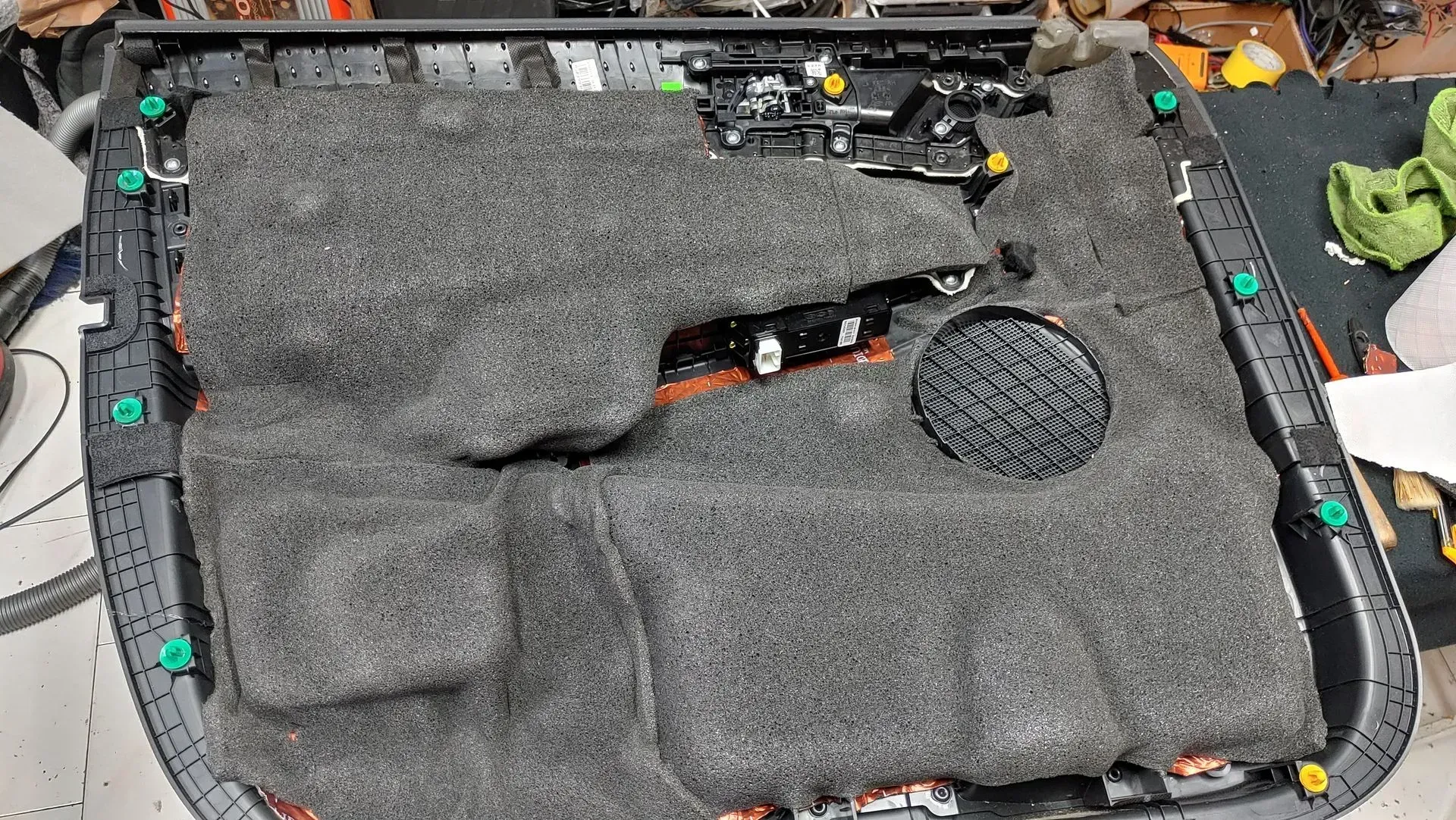 Panel de la puerta del coche, aislamiento de espuma gris, desmontado. Clips verdes, marco negro, electrónica visible.