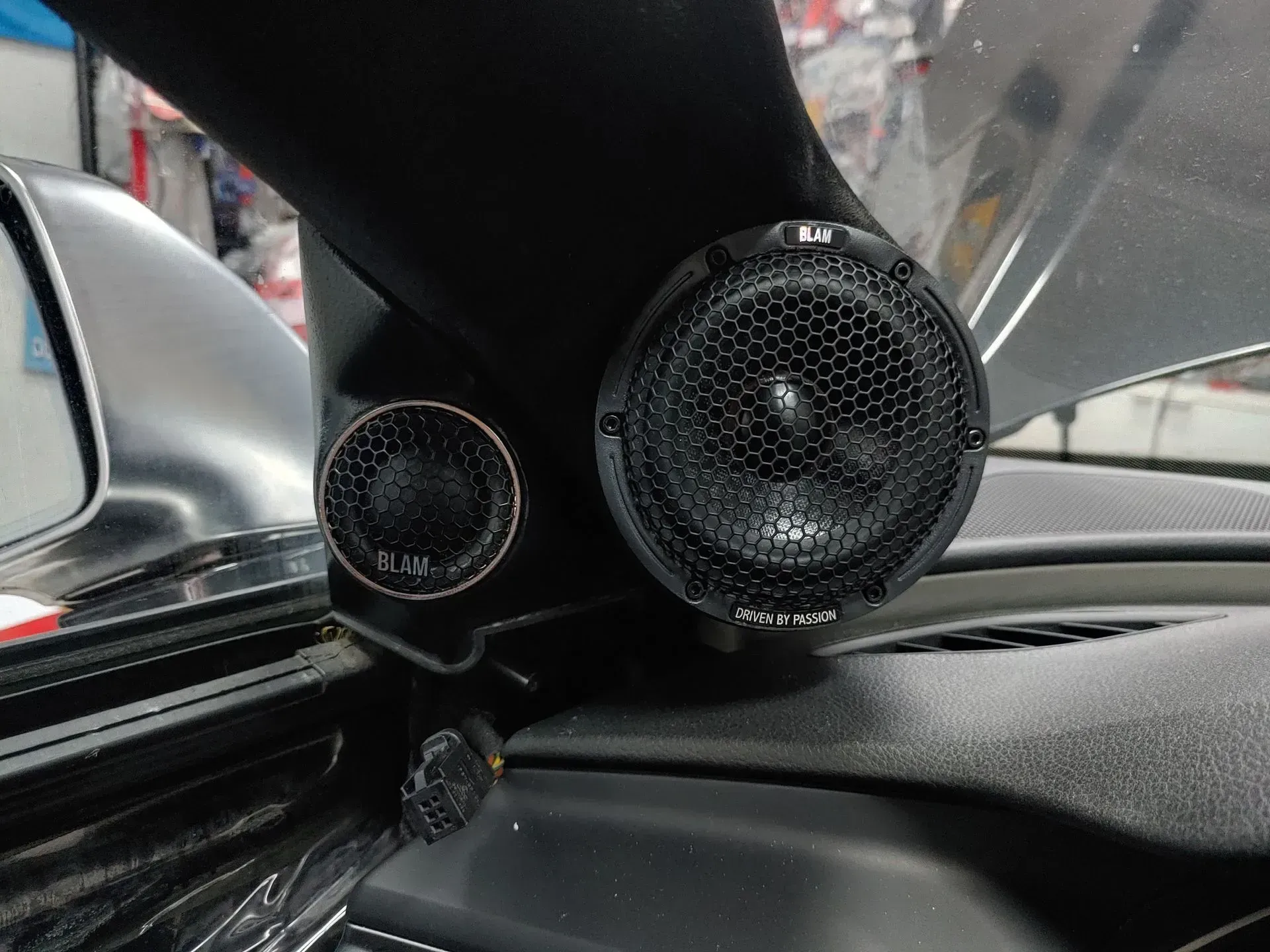 Dos altavoces de audio para automóvil de color negro montados en un tablero, uno más grande que el otro.