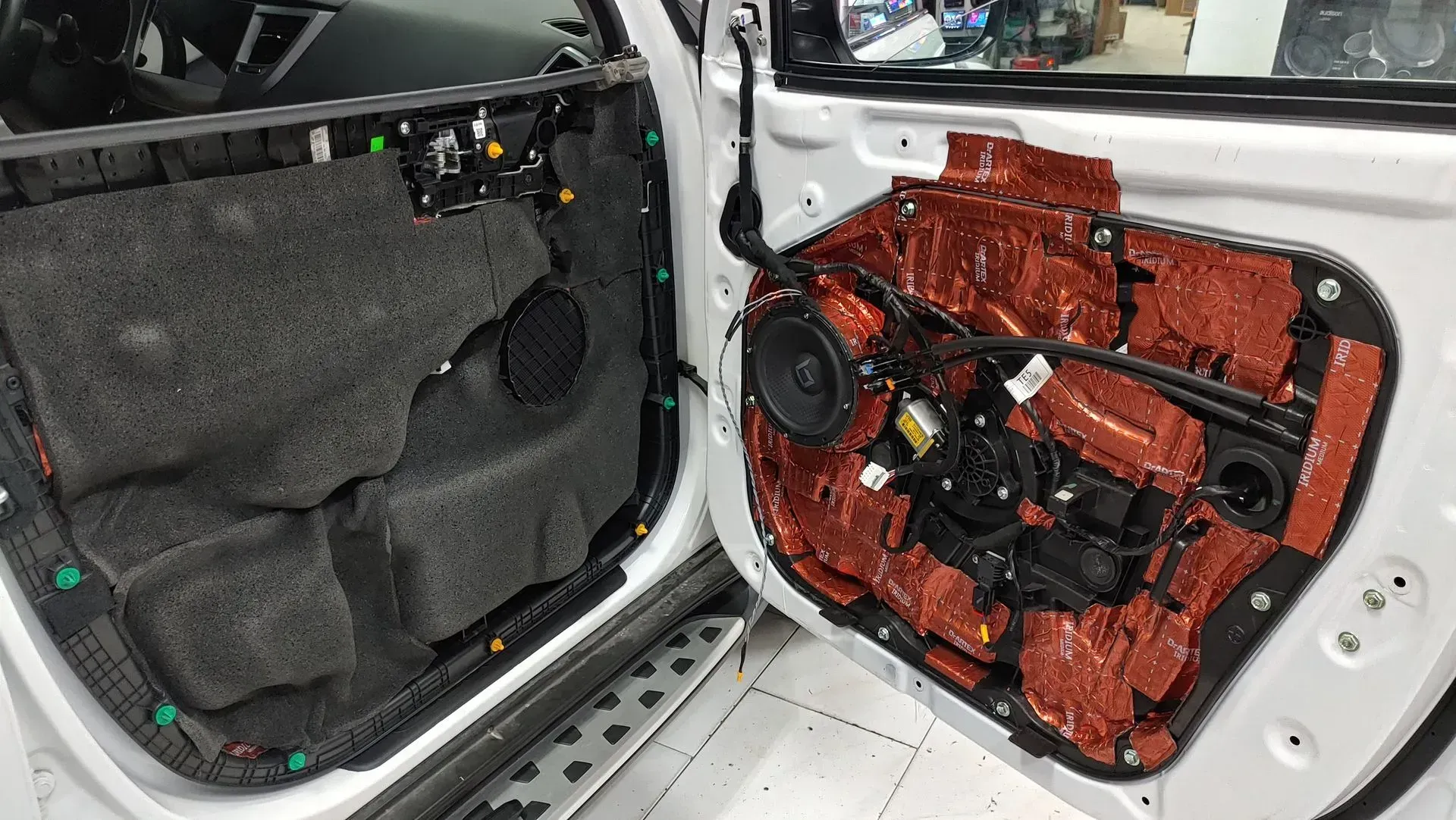 Interior de la puerta del coche con aislamiento expuesto, altavoz visible, en proceso de modificación.