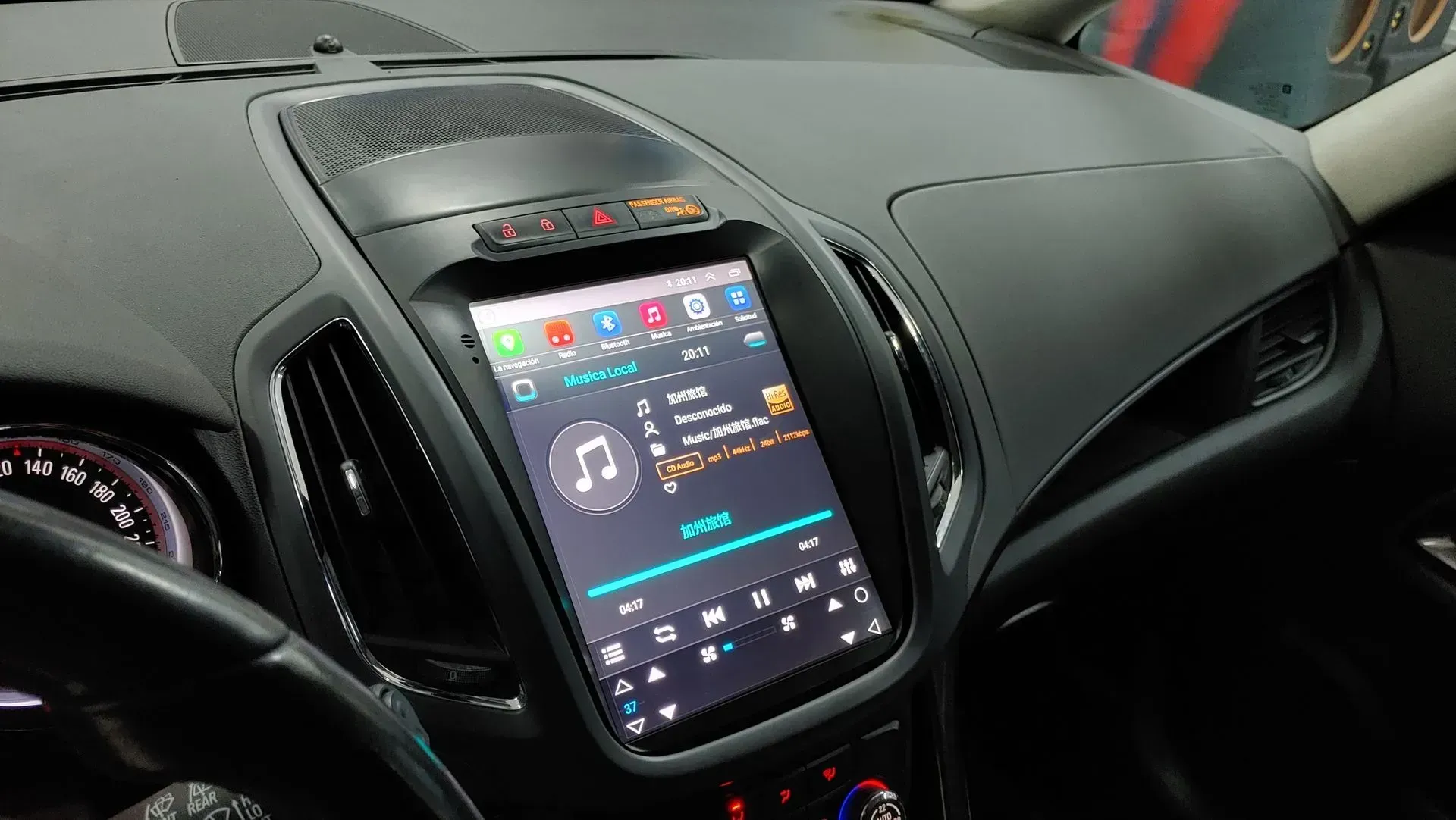 Tablero de instrumentos del automóvil con una gran pantalla táctil que muestra controles de música e íconos.