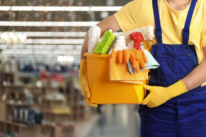 Un professionnel du ménage tient des produits de nettoyage