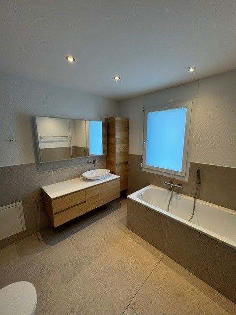 Modernes Badezimmer mit Holzwaschtisch, Badewanne und Fenster.