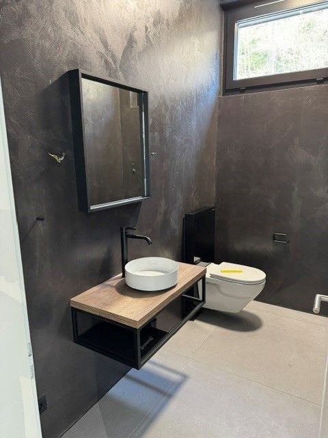 Modernes Badezimmer mit einem Waschtisch aus Schwarz und Holz, einem weißen Waschbecken und dunkelgrauen Wänden.