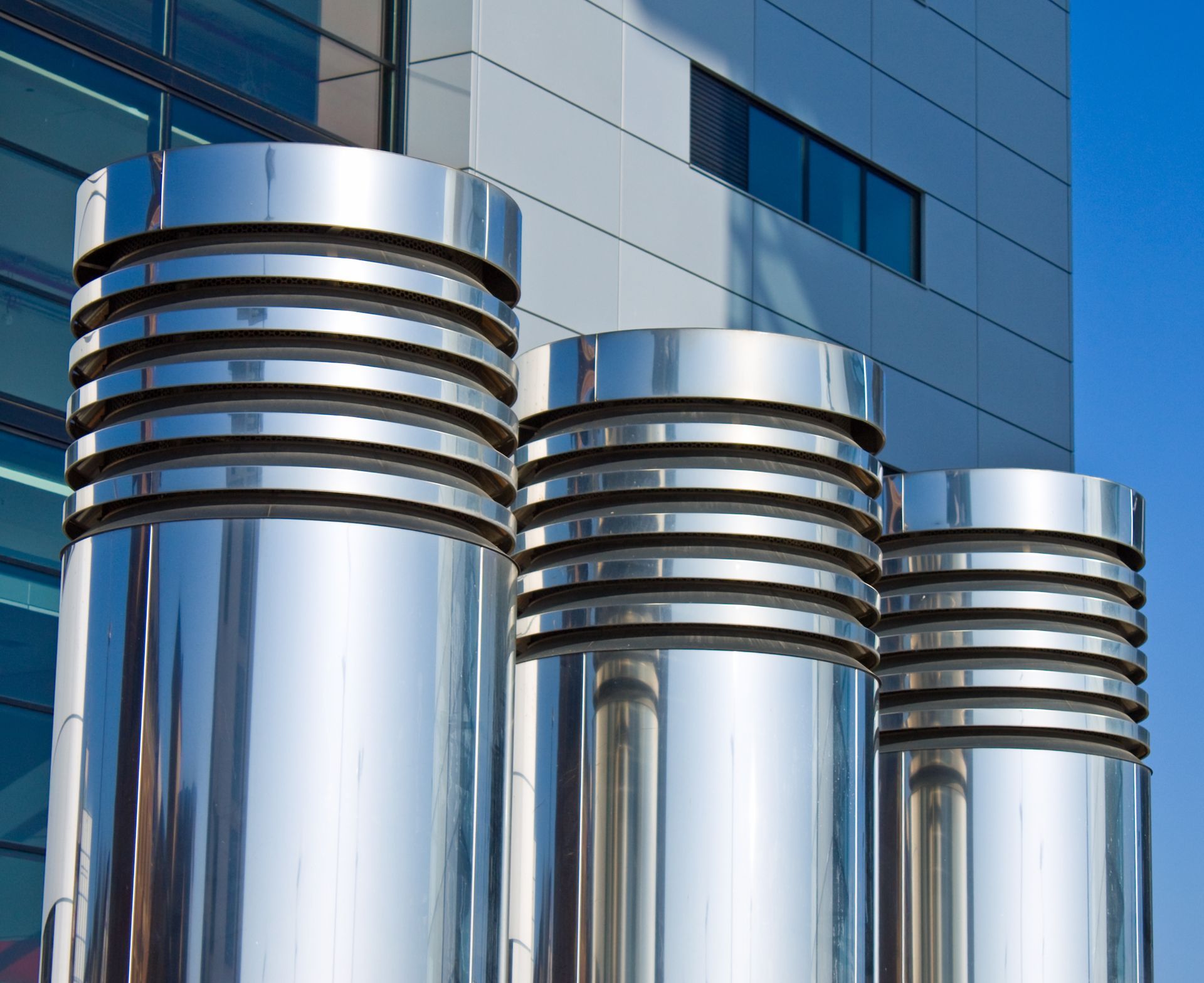 Komplexes System aus Rohren, Messgeräten und Pumpen in einer Industrieumgebung mit Metalltanks vor einer Betondecke.