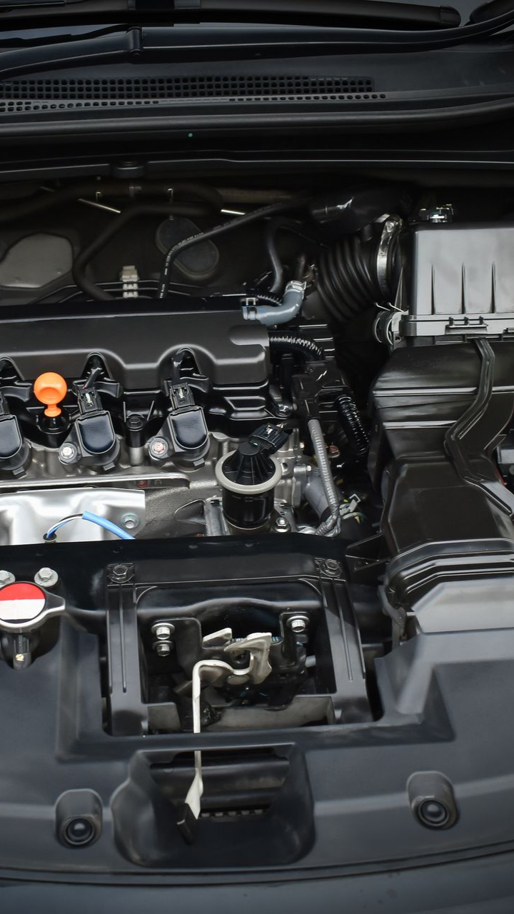 Compartiment moteur d'un véhicule ; composants et tuyaux noirs, diverses pièces visibles.