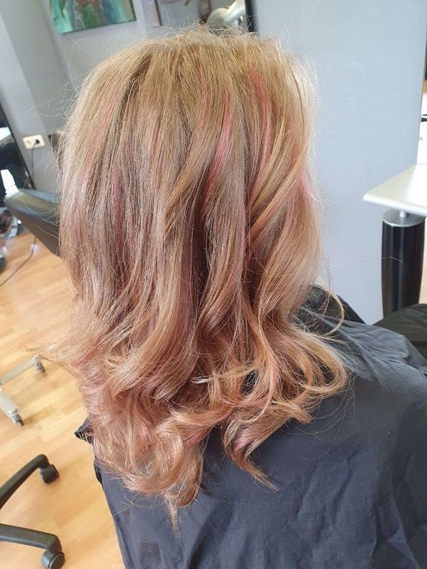 Eine Frau sitzt in einem Friseursalon auf einem Stuhl und frisiert.