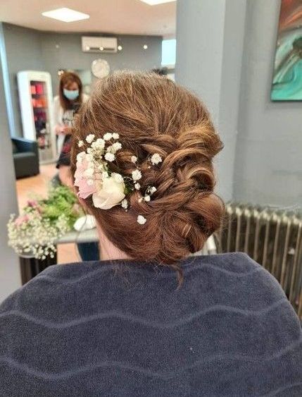 Eine Frau lässt sich in einem Friseursalon die Haare machen und hat Blumen im Haar.