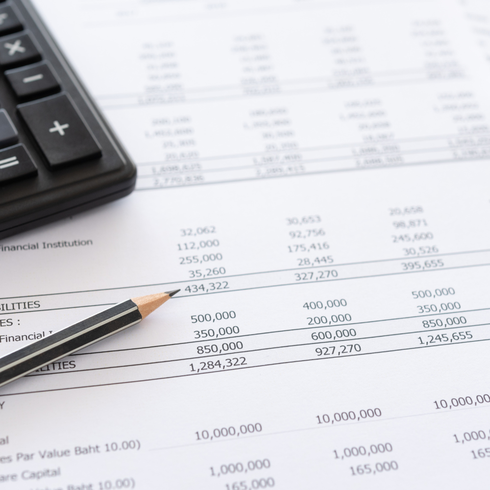 Calculadora, lápiz y documentos financieros con números y datos.