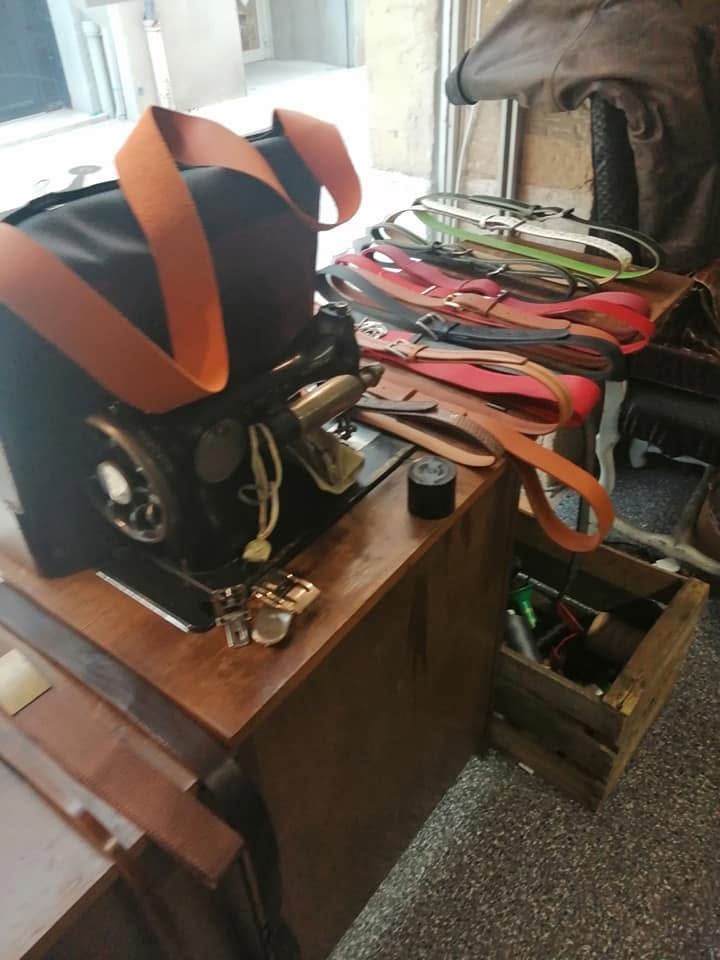 Un sac de sport noir et orange à côté d'un bureau en bois encombré d'outils et de sangles dans une pièce