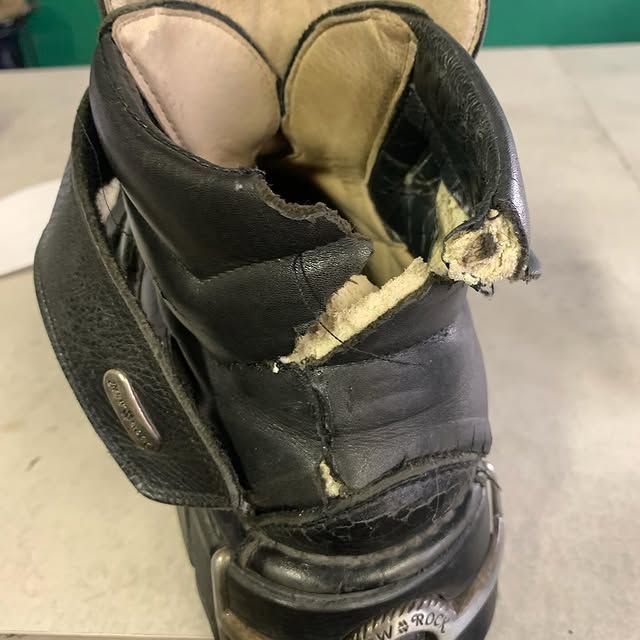Botte noire abîmée avec doublure beige déchirée, gros plan sur une table