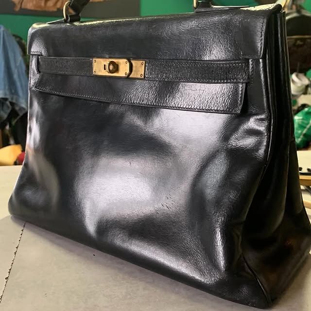 Sac à main en cuir noir avec fermoir doré posé sur une table