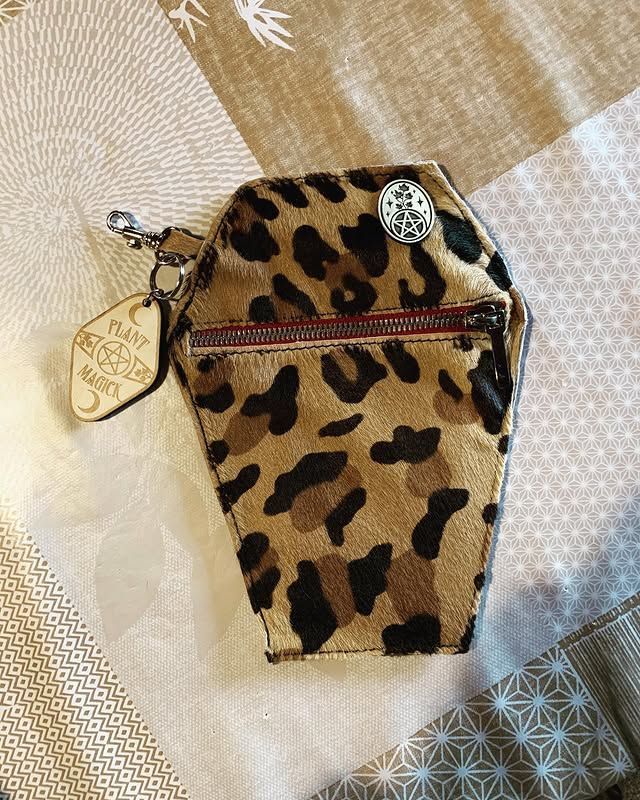 Porte-monnaie à imprimé léopard avec fermeture éclair et anneau porte-clés sur fond de tissu à motifs