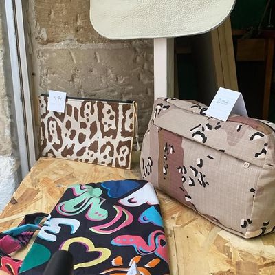 Sacs à motifs assortis et pochettes en tissu sur une table en bois à côté d'un mur en pierre.