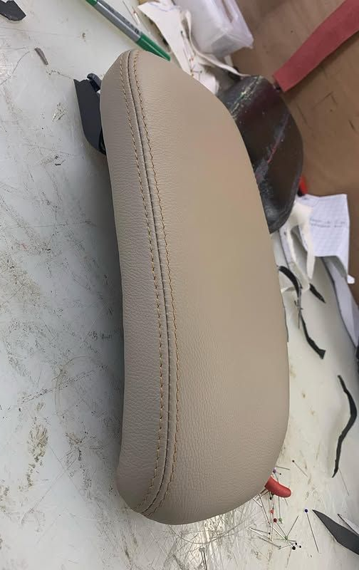 Siège de moto beige posé sur une table encombrée de papiers et de câbles.
