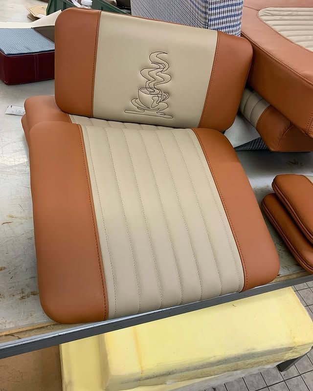 Fauteuil lounge beige et taupe avec coussins et broderies de serpent, exposé dans un magasin de meubles.