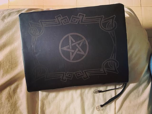 Carnet ou classeur en tissu noir avec un motif pentagramme sur une couverture beige, avec un cordon attaché