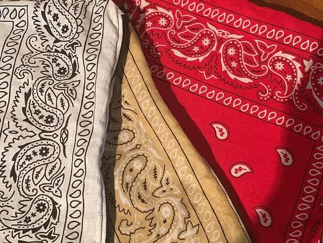 Gros plan sur des tissus bandanas à motifs rouges, beiges et noirs superposés.
