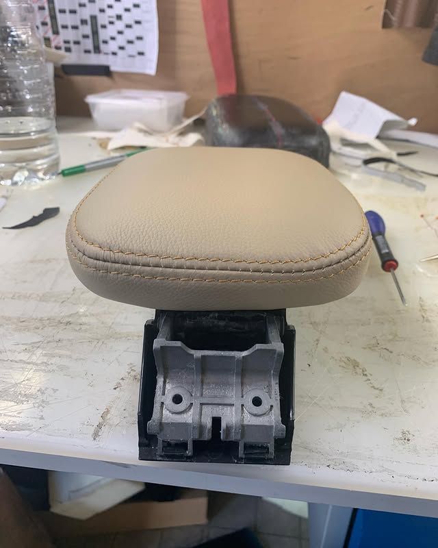 Coussin de siège beige recouvert de tissu, monté sur un socle en métal noir, sur un établi.
