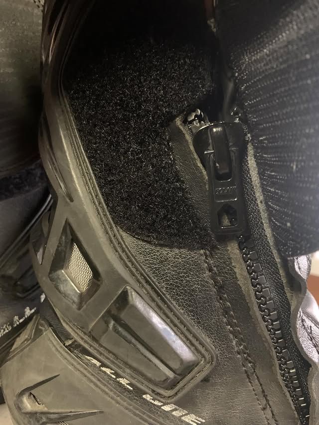 Gros plan sur une botte noire à fermeture éclair, en tissu texturé avec des finitions réfléchissantes.