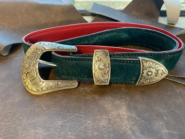 Ceinture en daim vert avec boucle dorée ornée et détails sur une surface en bois
